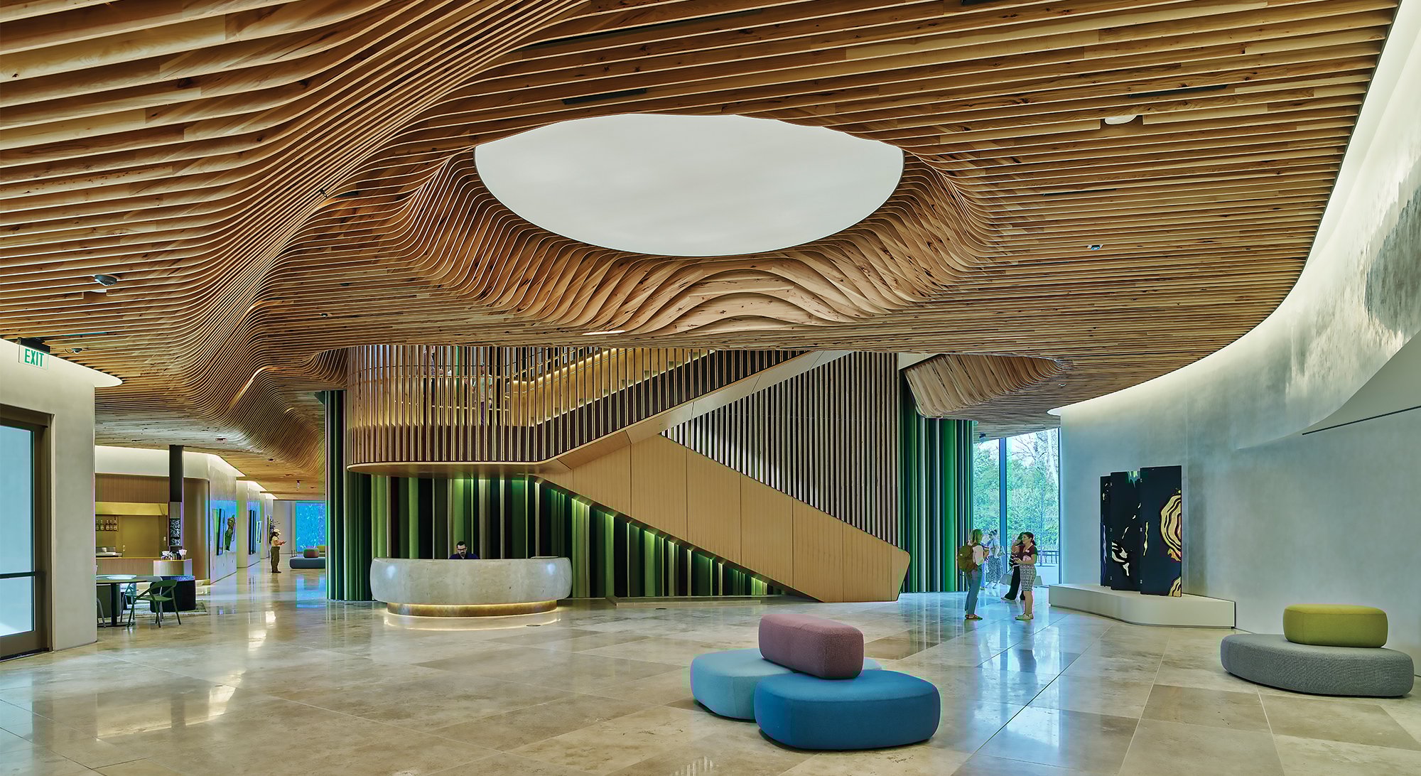 Inside the the lobby of the Heartland Whole Health Centre that is made with mass-timber constructed ceilings and a pebble like furniture and a few people talking in the bakground. 