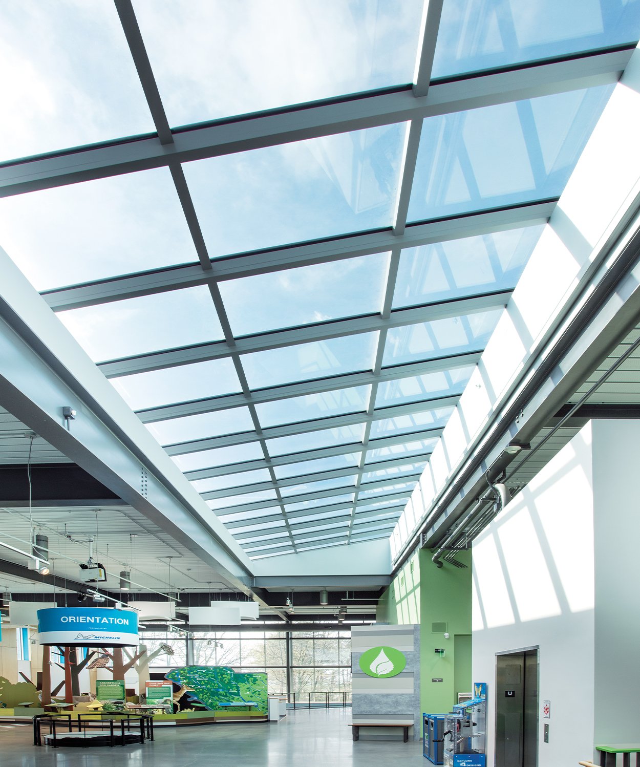 A corporate office space with smart building solution added in the form of metal framed clear glass skylight filling the space with natural lights. 