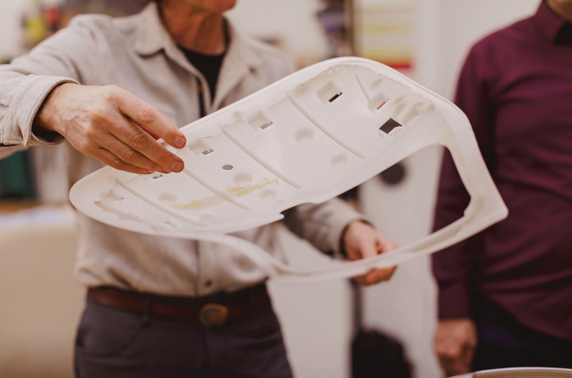 A person holding the base of the seat of an office chair made in recycled plastic. 
