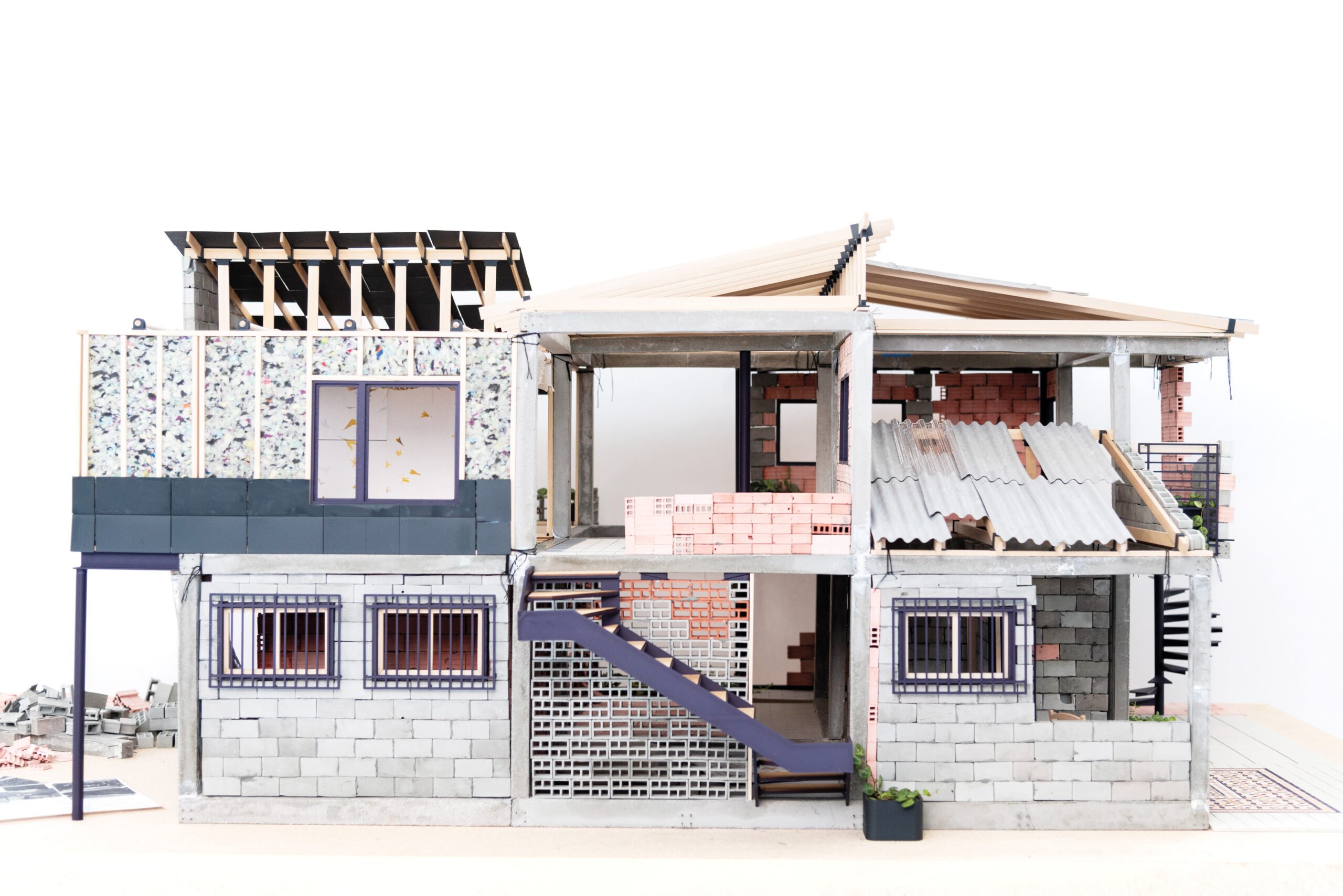 A 3D model of a sustainable house made using paper and other miniature materials showcasing reuse of discarded construction materials. 