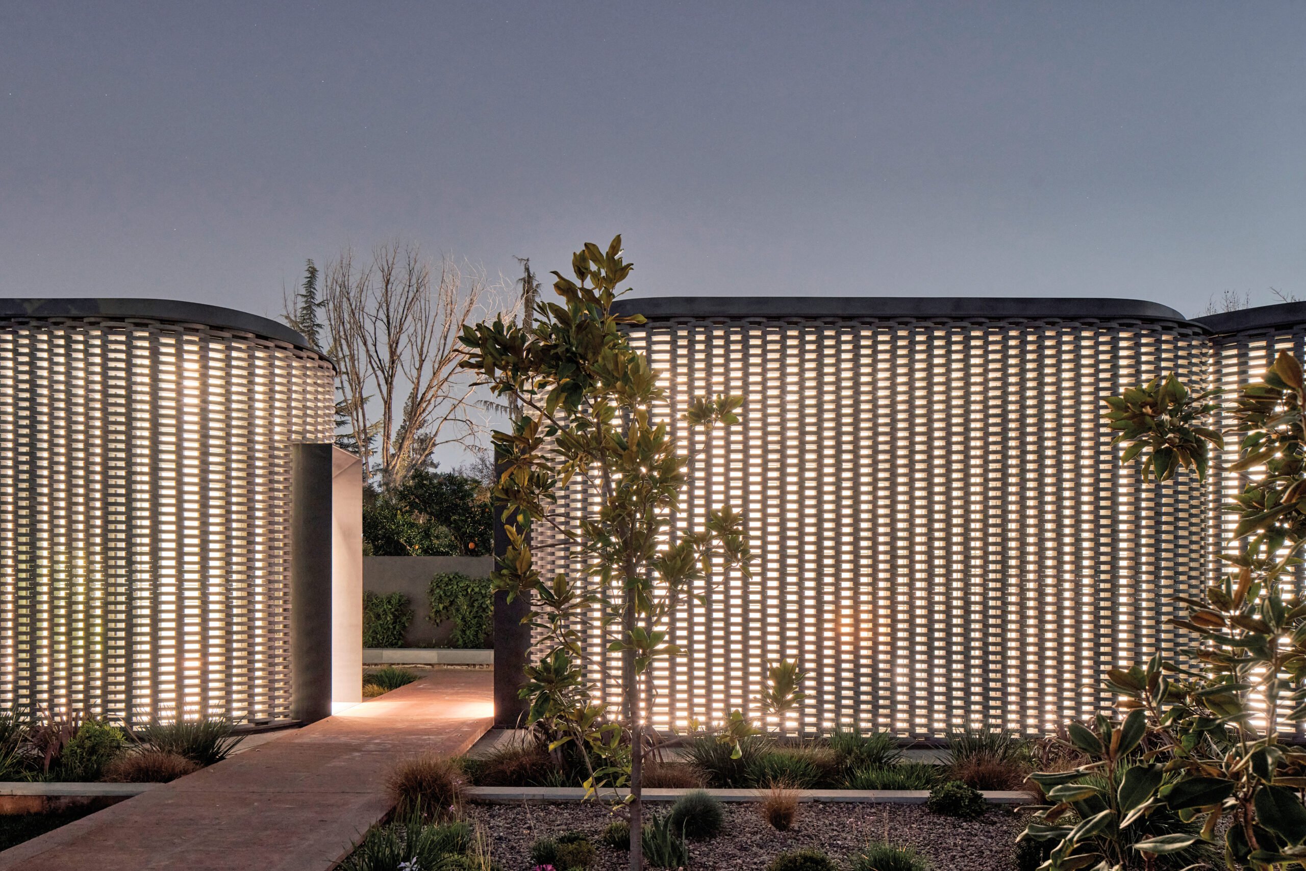 the entrance of a space with backlit concrete brick walls and lots of greens on the exterior. 