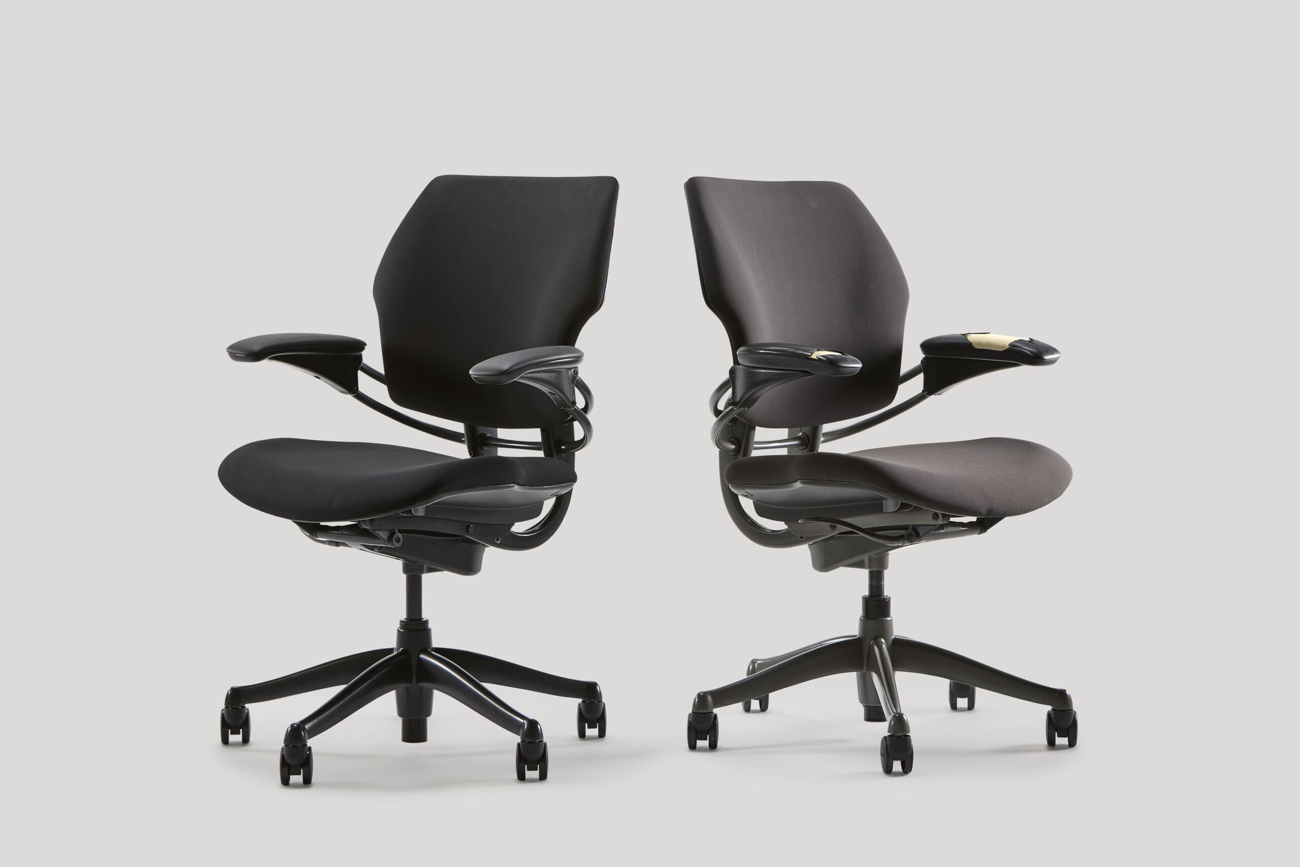 2 black work chairs, left new, finished and polished while right is old worn out and torn.