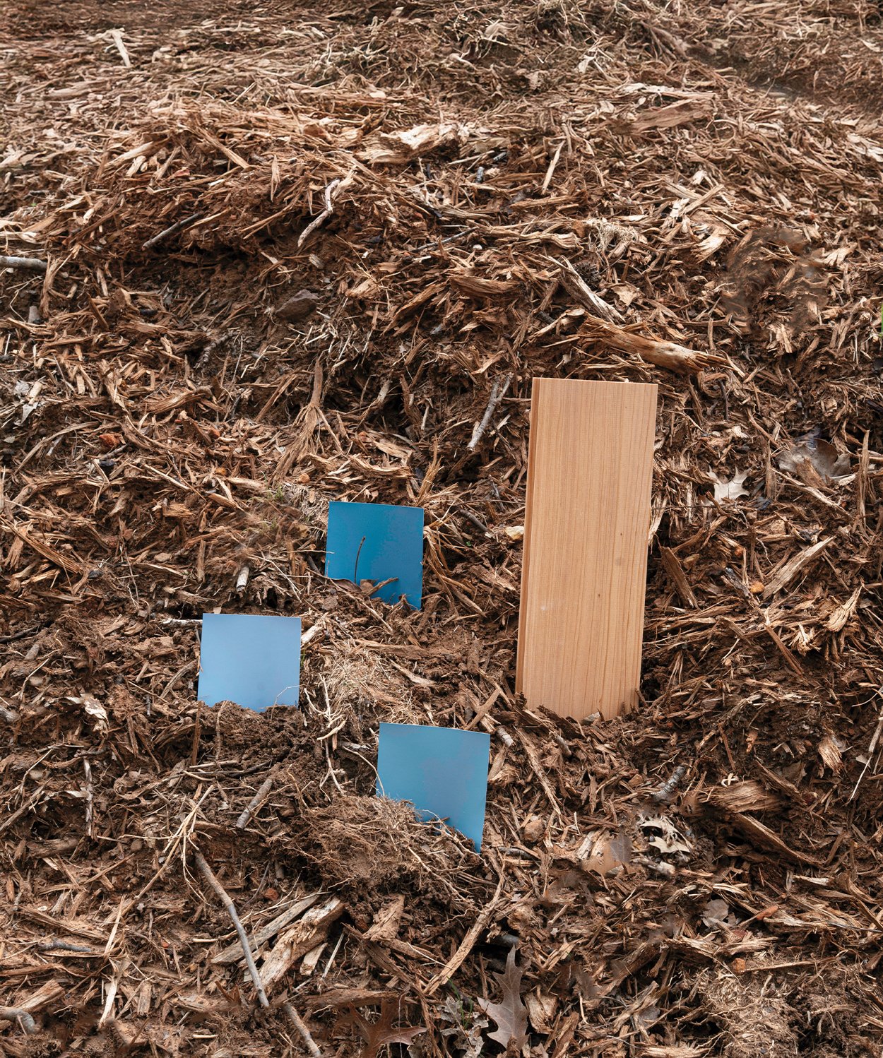 swatches of blue and wood pieces places in a pile of hay. 