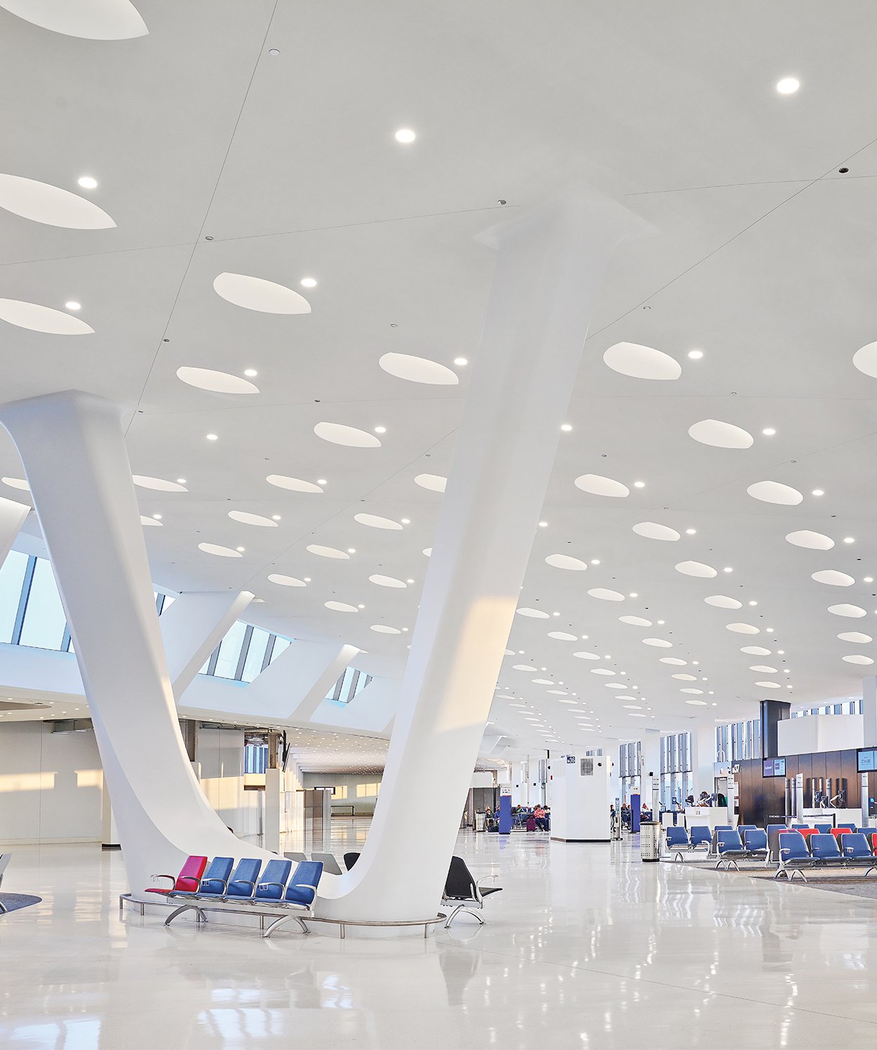 Smart building drywall solution system installed at an airport lobby in white with blue seats making the space look large and light up. 